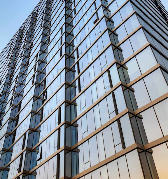 A tall building with many windows and a blue sky in the background.