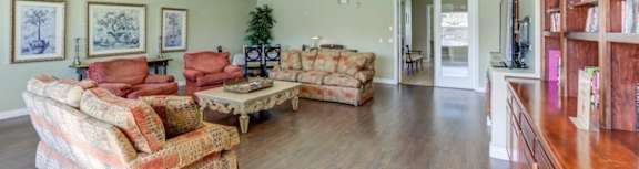 A living room with a sofa set and a ceiling fan.