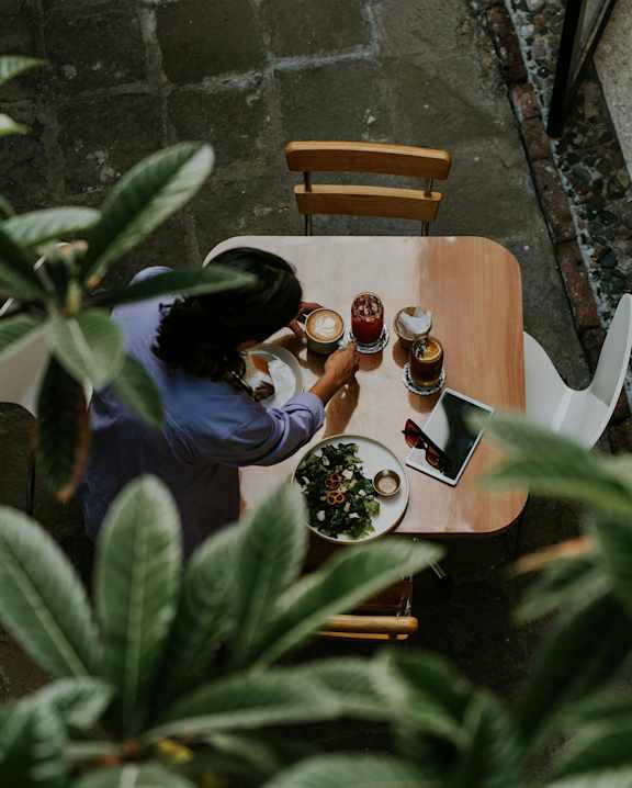 A woman is sitting at a table with a plate of food and a cup of coffee.