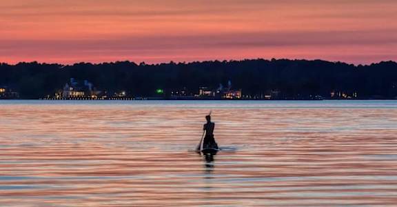 a person in a canoe on a lake at sunset