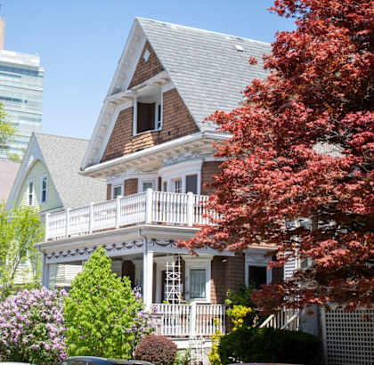 a row of houses with trees and a skyscraper in the background