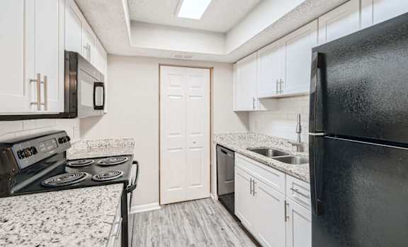A kitchen with black appliances and white cabinets.