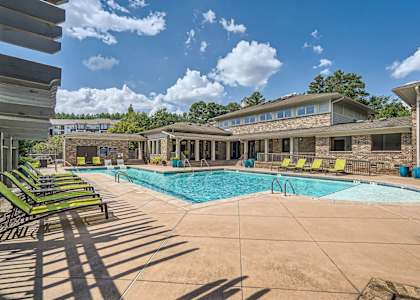 A swimming pool surrounded by lounge chairs and a building in the background.