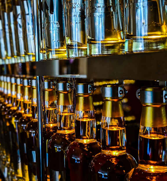 A row of bottles with amber liquid in them are lined up on a shelf.