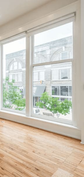 an empty living room with a ceiling fan and large windows