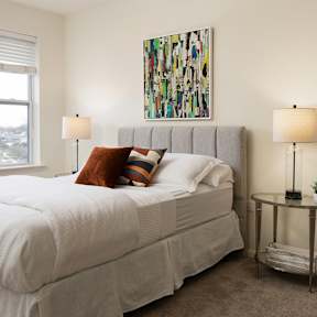 A bedroom with a large bed and a painting on the wall.
