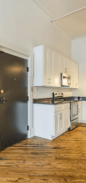 a kitchen with white cabinetry and black countertops
