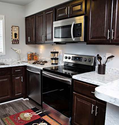 A kitchen with dark wood cabinets and a white marble counter.