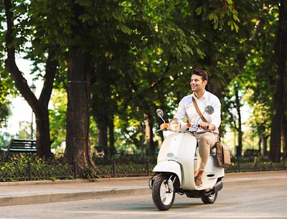 a man riding a white scooter down a street