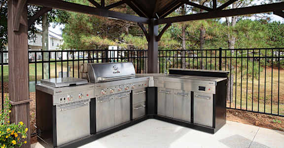 A BBQ grill set up under a wooden pavilion.