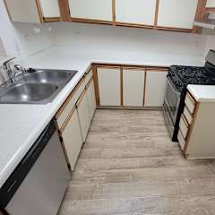 A kitchen area with a sink, cabinets, and a window.