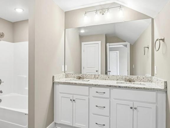 A bathroom with a marble countertop and white cabinets.