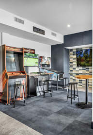 a room with arcade machines and tables and a bar