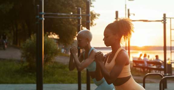 Two women exercising in a park during sunset.