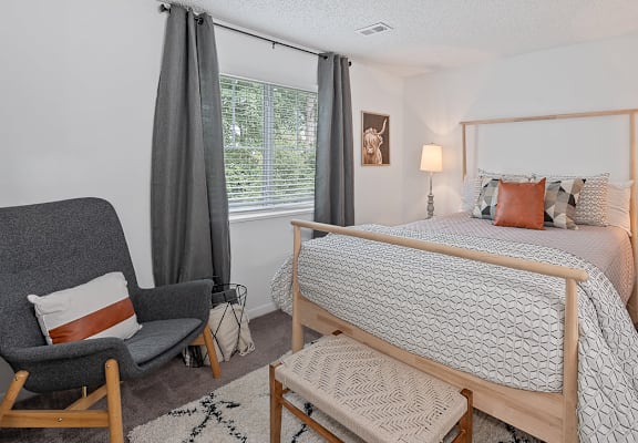 a bedroom with a bed and a chair and a window
