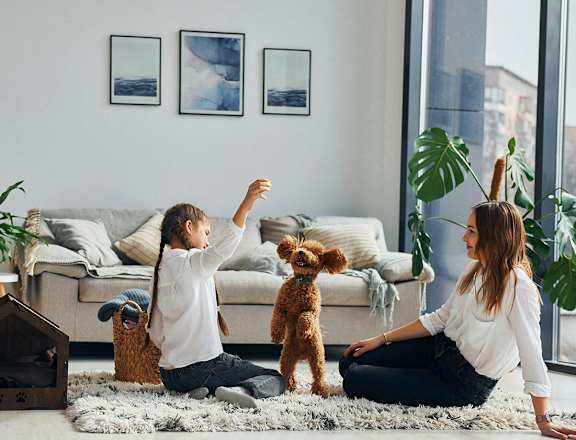 a woman and a child sitting on the floor in a living room with a dog