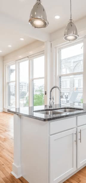 a kitchen with a large window and hardwood floors
