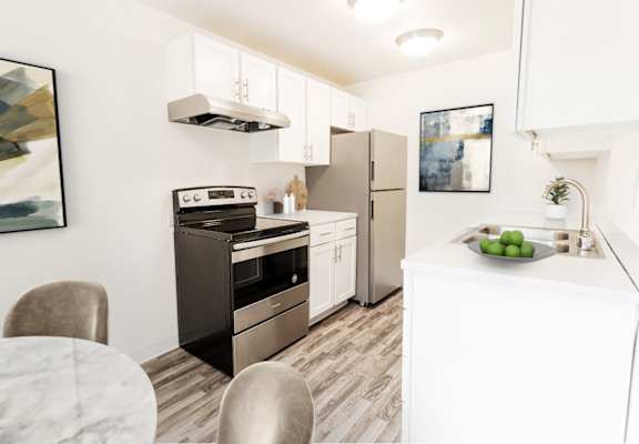 A modern kitchen with a stove, refrigerator, and a table with chairs.