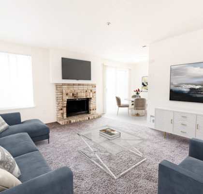 A living room with a grey sofa, a fireplace, and a television.