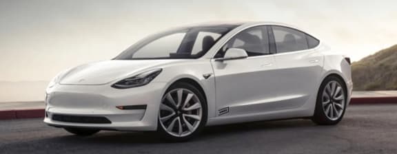 White Tesla Model 3 parked roadside in the afternoon.