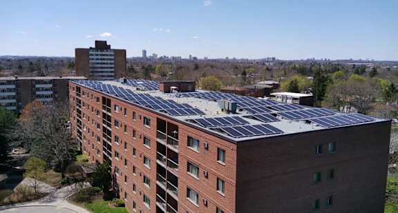 An orange a grey building with sun panels on the top of its roof