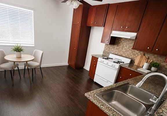 A kitchen with a table and chairs in the foreground and a stove in the background.