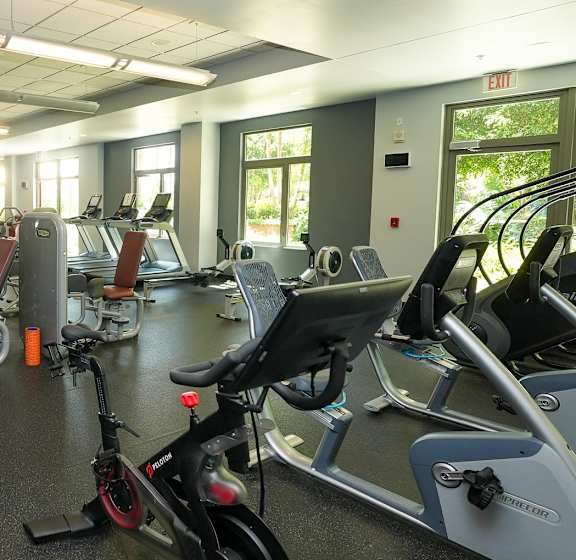 A gym with a variety of exercise equipment including treadmills, stationary bikes, and weight machines.
