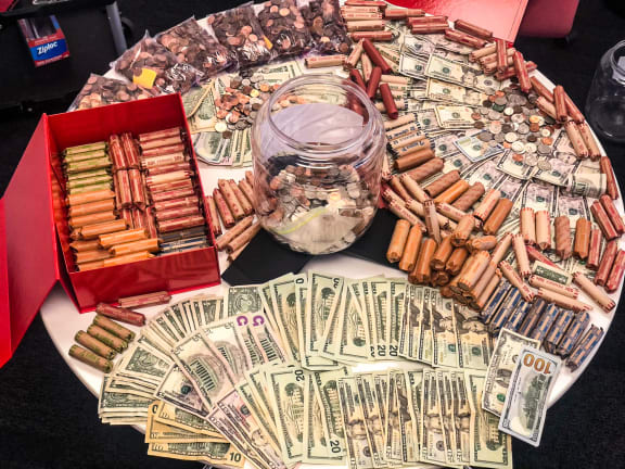 a table topped with a glass jar filled with money and a pile of cigars