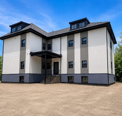 A modern two-story house with a flat roof and a balcony on the second floor.