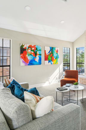 Cozy lounge space in clubhouse with fireplace, couch and orange plush seats at Bandera Crossing apartments in San Antonio, TX
