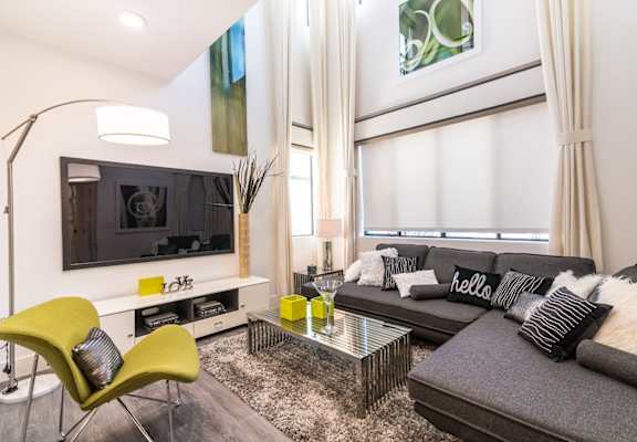 A living room with a tv and blinds and couch and chairs and coffee table