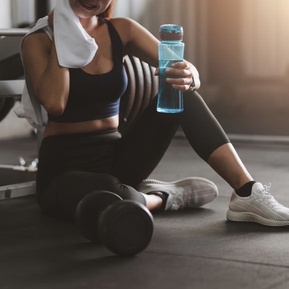 a woman sitting on the floor with a towel around her neck and holding a bottle of water at Madison at Eden Brook, Maryland, 21046