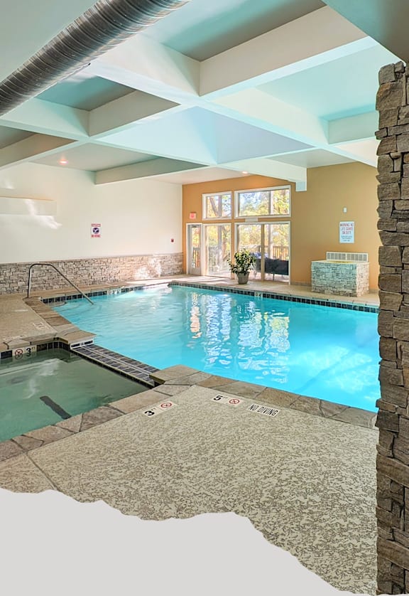 A small indoor swimming pool with a bench and a stone pillar.