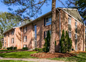 Thumbnail 28 of 40 - Brick apartment building with mature landscaping at The Brook At Columbia Apartments, Columbia, MD 21044