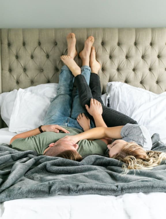 a couple laying on a bed with their legs up on top of each other
