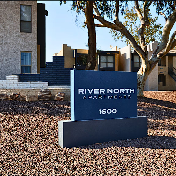 A sign for River North Apartments stands in front of a building.