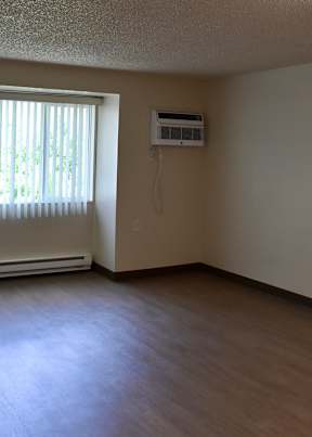 A room with a window and air conditioner on the wall.