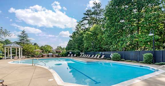 a resort style pool with chairs around it and trees