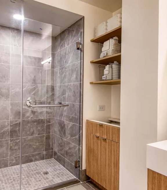 A modern bathroom with a walk-in shower and a white sink.at 301E94, New York, 10128