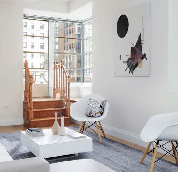 A white chair sits in a living room with a white couch and a white coffee table.at 21 West, New York