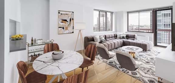 A modern living room with a large window and a grey sofa at The Ellington Apartments, New York, NY, 10019
