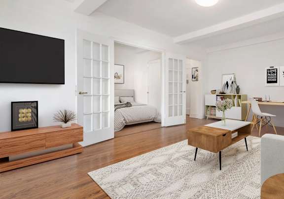 A modern living room with a grey couch, a wooden coffee table, and a flat-screen TV mounted on the wall.at London Terrace Gardens, New York, NY 10011