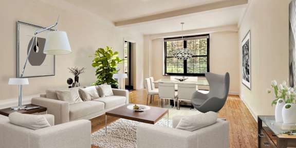 A living room with a grey sofa, a white armchair, a wooden coffee table, and a large window with a view of a garden.at London Terrace Gardens, New York