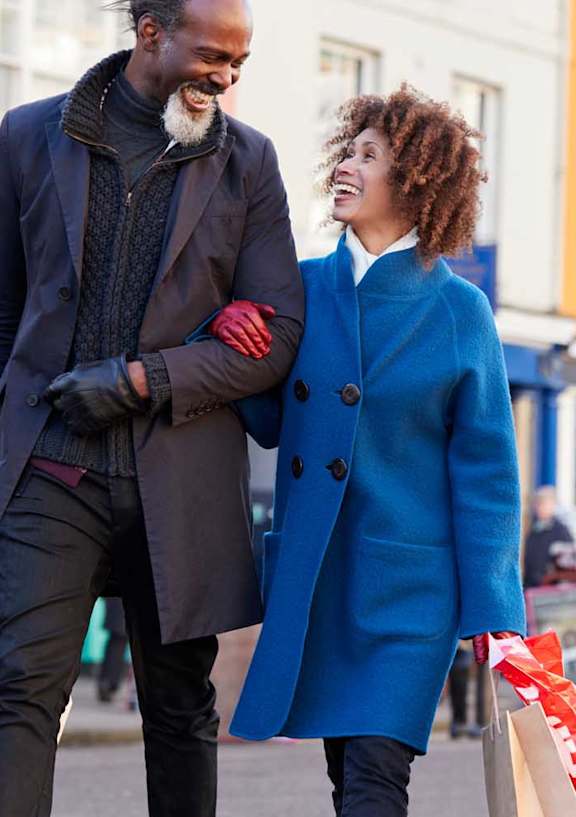 a man and a woman walking down a street holding shopping bags