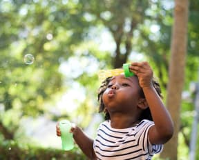 a young girl playing with a soap bubble
