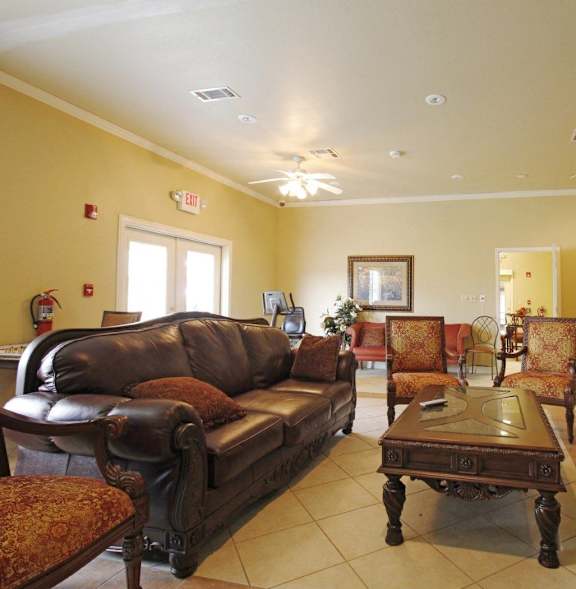 A living room with brown leather furniture and a ceiling fan.
