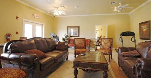 A living room with brown leather furniture and a ceiling fan.