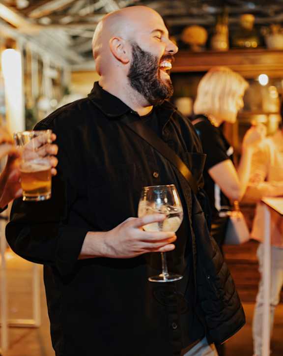 A man with a beard is holding a glass of wine.