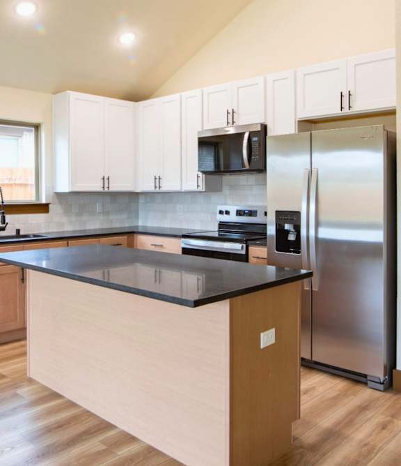 A kitchen with a refrigerator, microwave, and oven.
