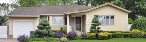 a house with a lawn and shrubs in front of it